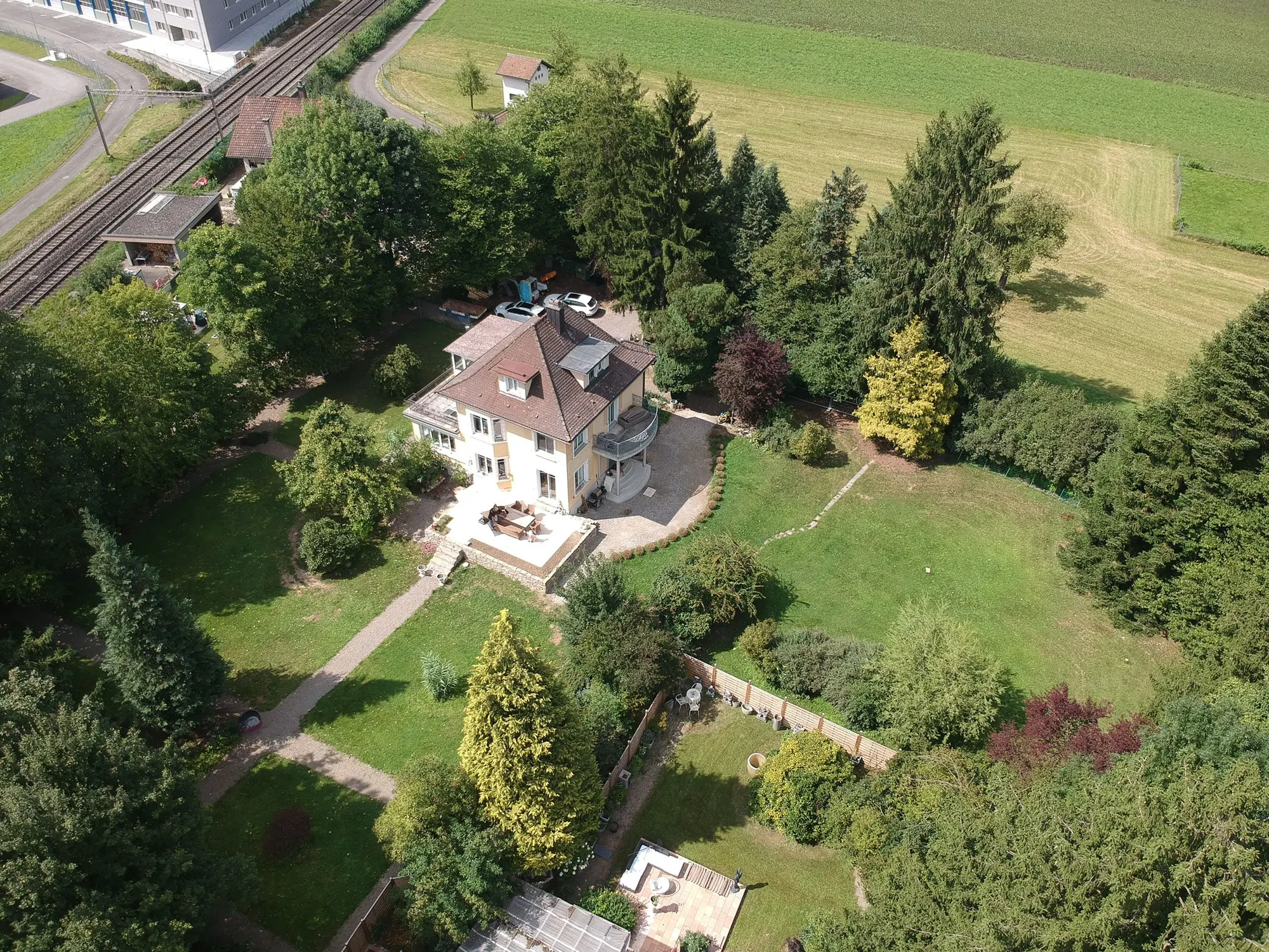 Luftaufnahme der Villa im Park mit Terrasse, Rasenflächen und altem Baumbestand