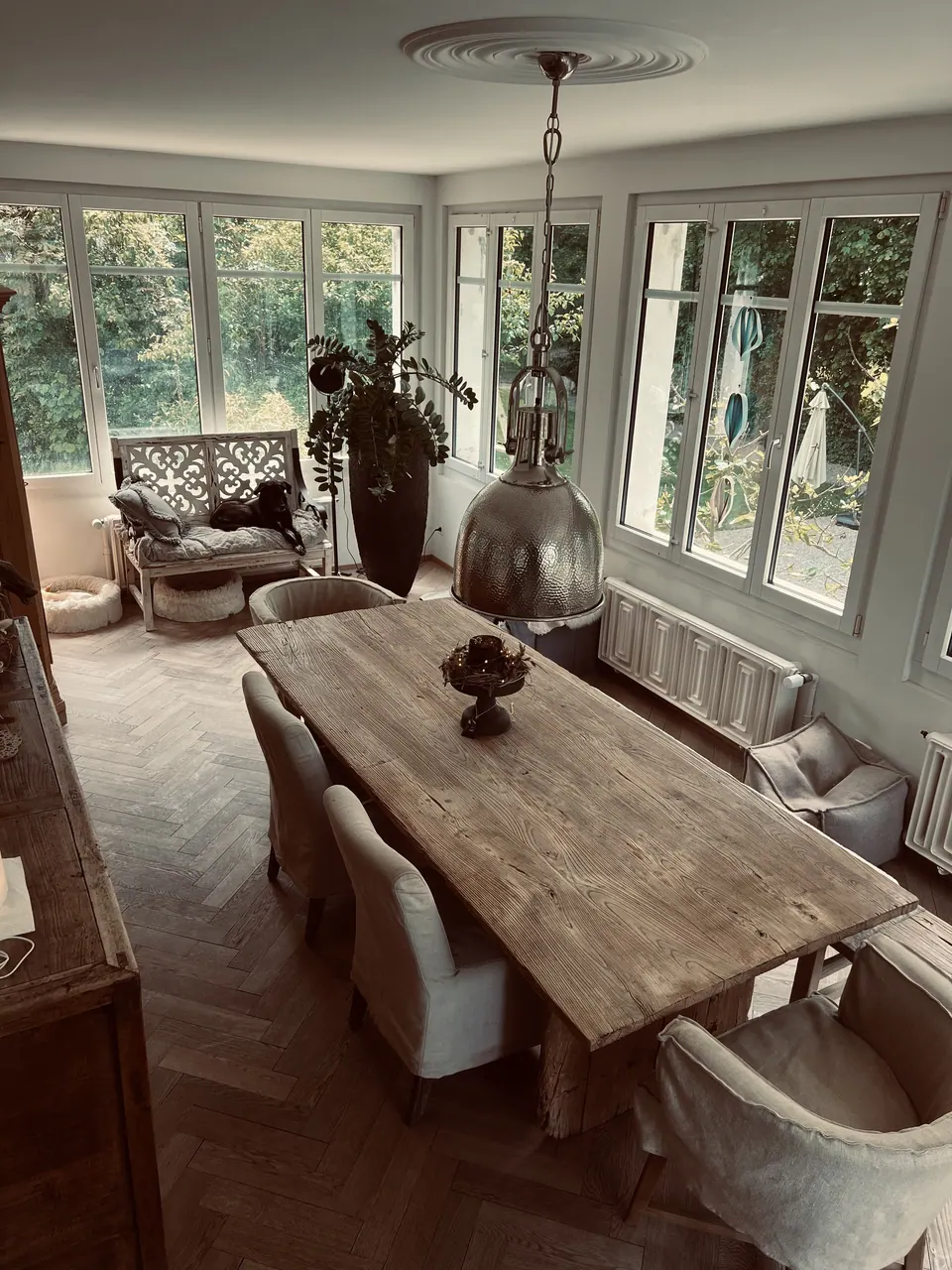 Heller Wintergarten mit grossem Holztisch und Sprossenfenstern